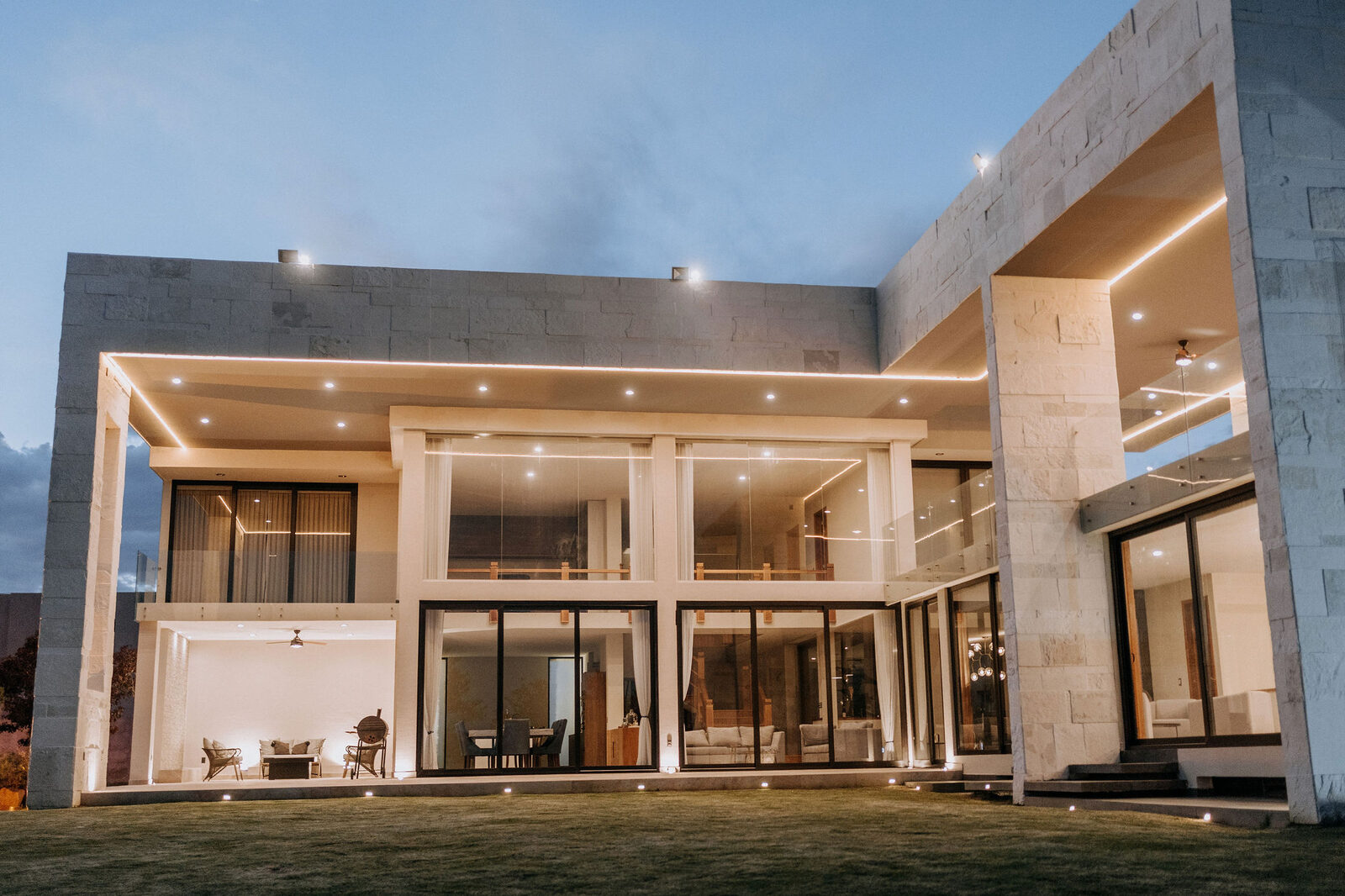 Residencia contemporánea de piedra y cristal al atardecer