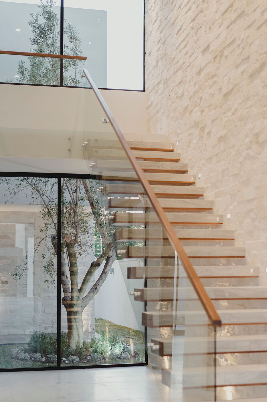 Escalera junto a muro de cristal con vegetación