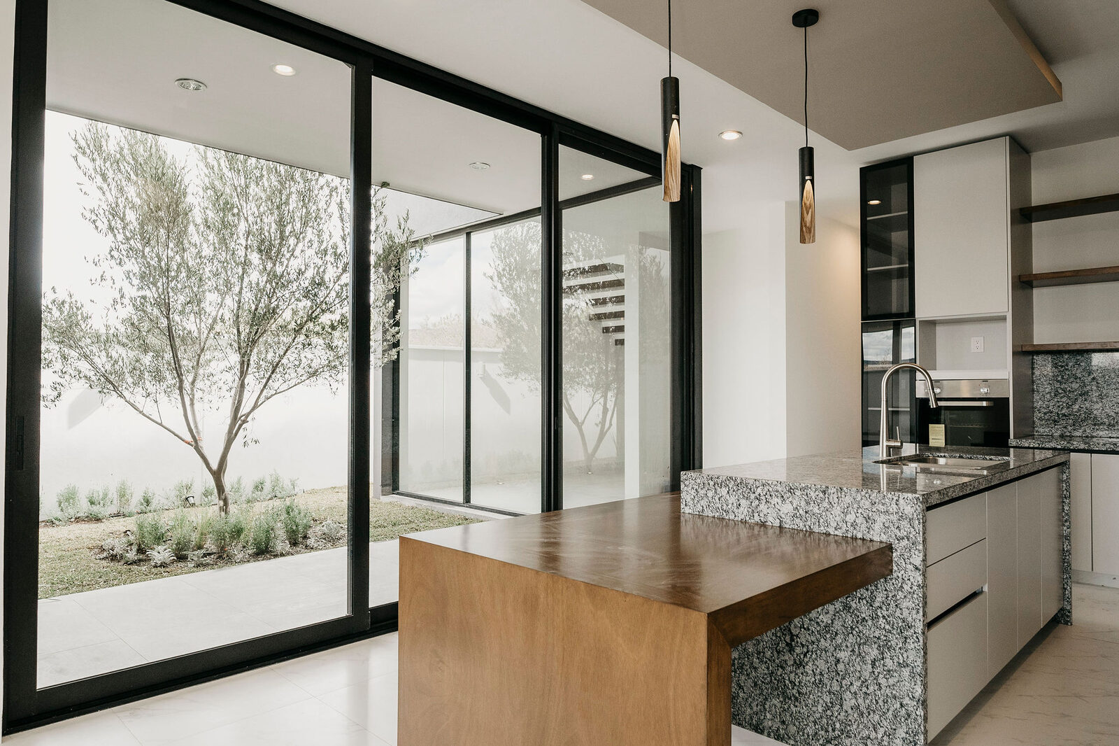 Cocina con muro de cristal y vista a un árbol